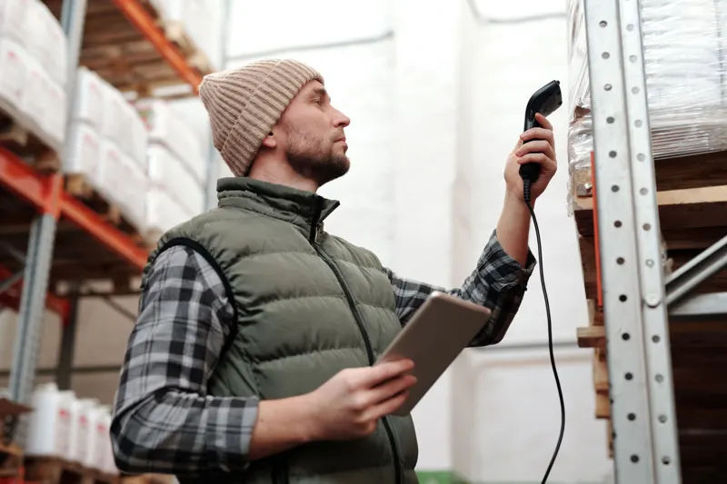 Warehouse worker using a handheld scanner and tablet to check stock